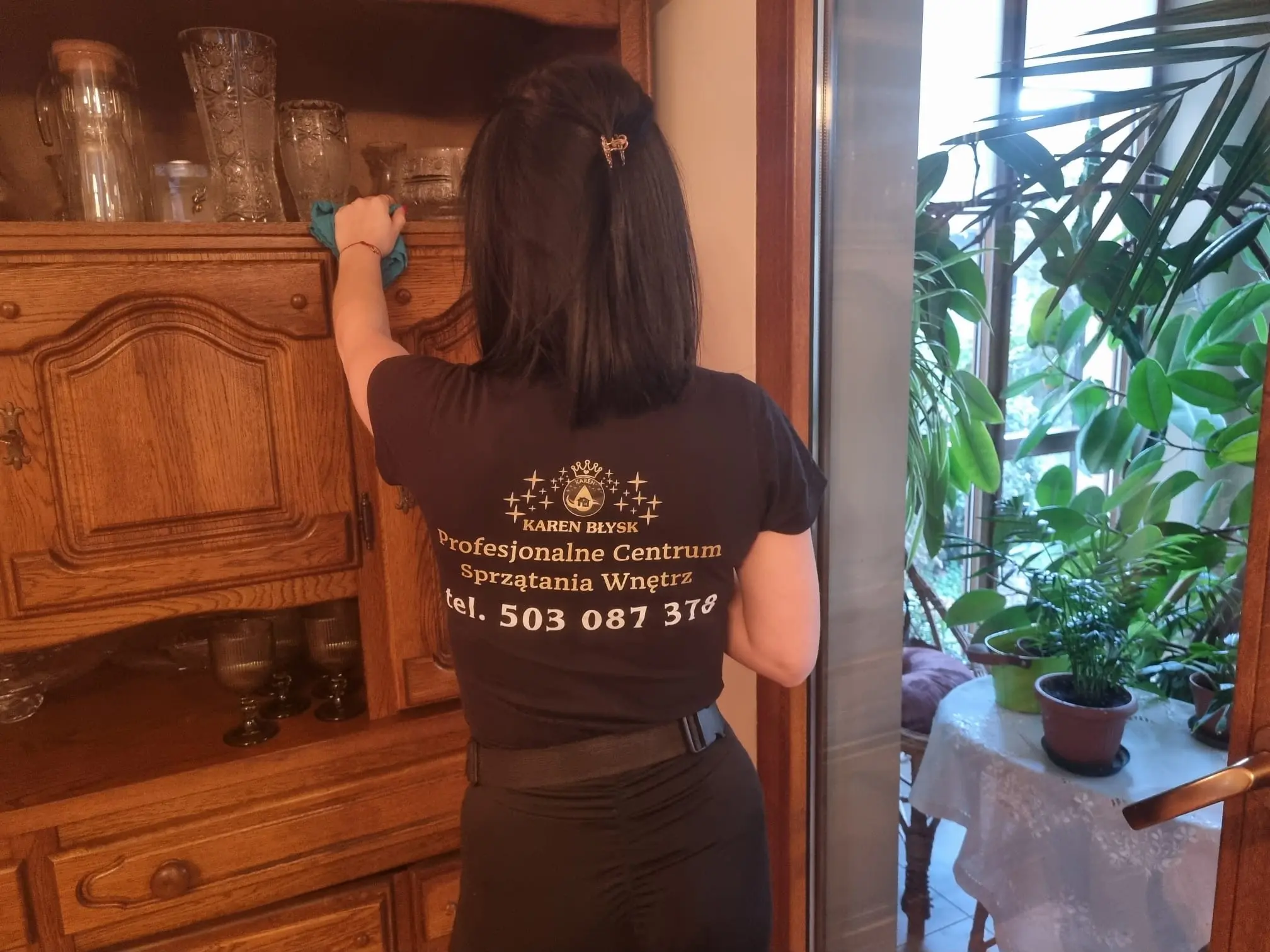 Sprzątaczka wycierająca kurze na komodzie w salonie – dokładne sprzątanie salonów z firmą Karen Błysk